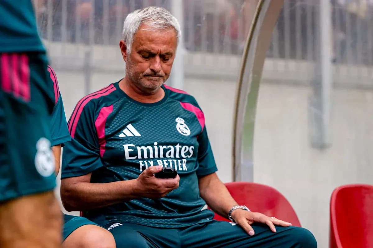 Entrenador de Real Madrid revisando su teléfono en banco Entrenador de Real Madrid revisando su teléfono en banco