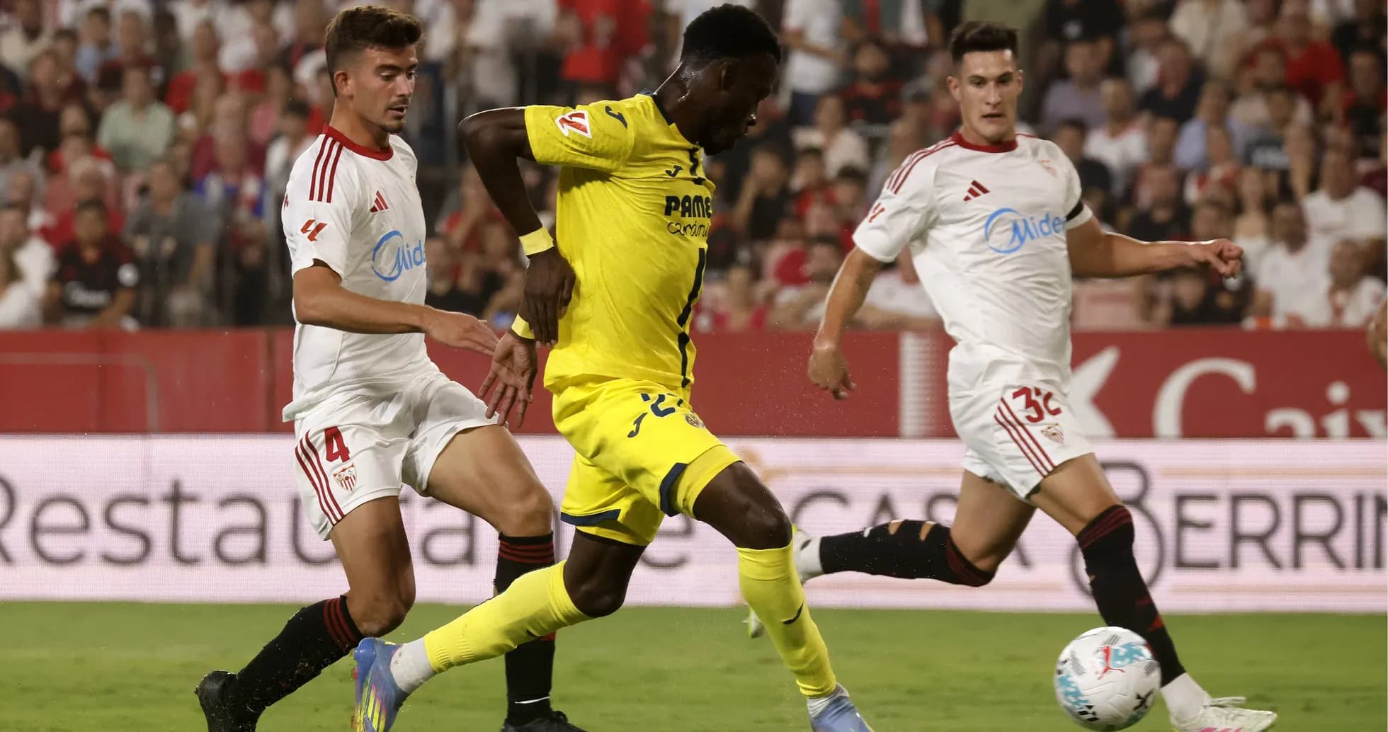 Jugador de Villarreal driblando a defensores de Sevilla Jugador de Villarreal driblando a defensores de Sevilla